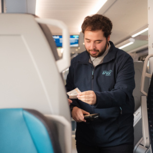 Fahrgastbetreuer im Zug mit Fahrscheinen in der Hand 
